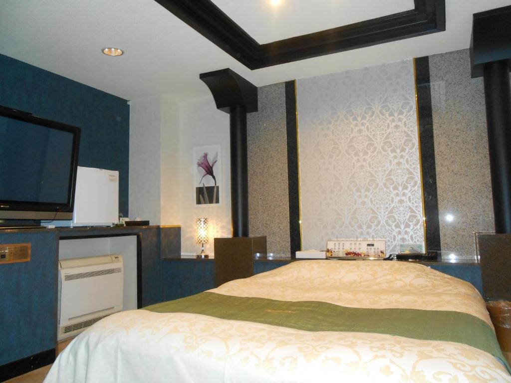 une chambre avec un lit et une télévision à écran plat dans l'établissement Hotel Regina, à Kashiwa