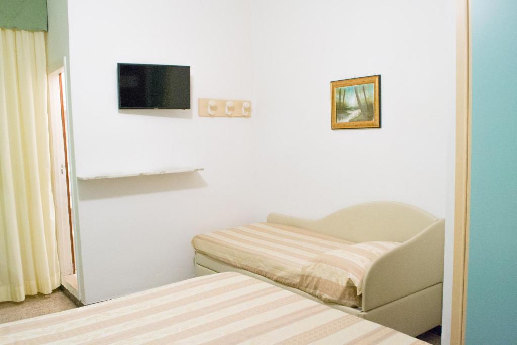 Cette chambre blanche dispose d'un lit et d'une télévision. dans l'établissement Hotel Solmar, à Cattolica