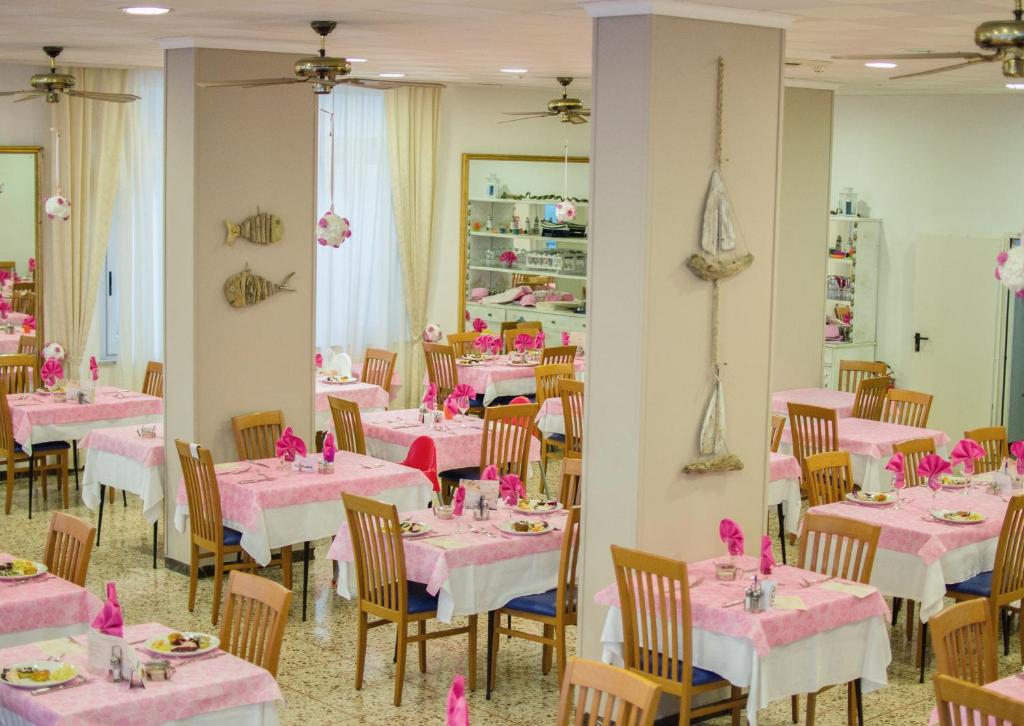 une salle à manger avec des tables et des chaises roses dans l'établissement Hotel Solmar, à Cattolica