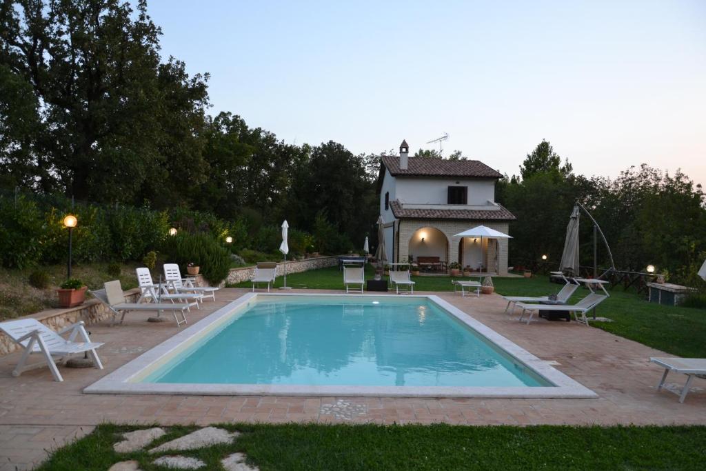 une piscine avec des chaises et une maison en arrière-plan dans l'établissement Casa di Romano, à Terni