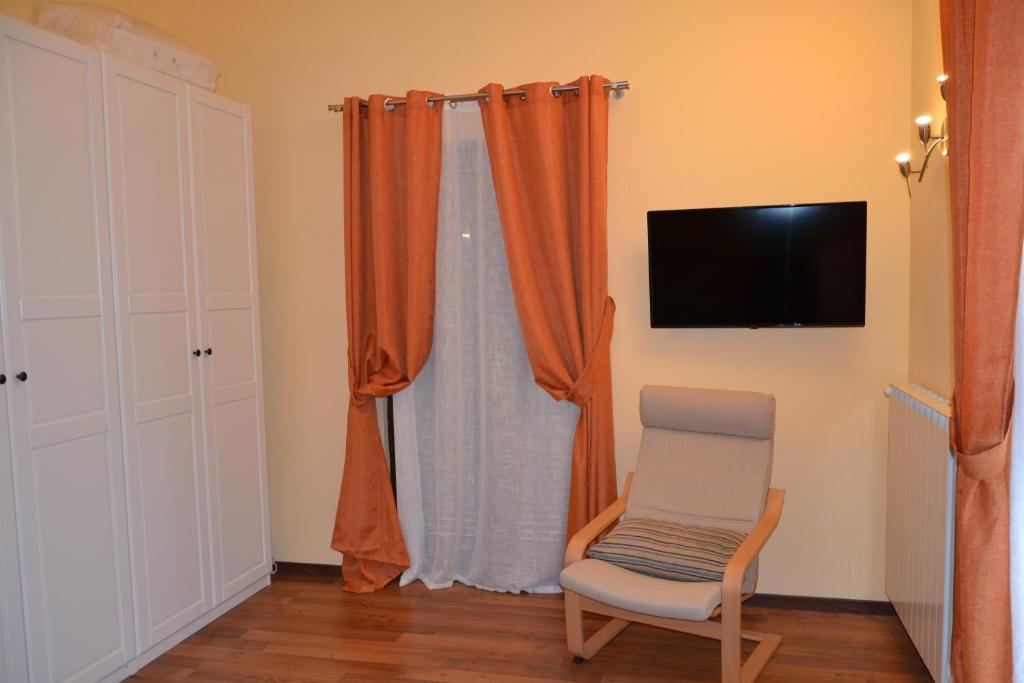 Cette chambre dispose de rideaux orange, d'une chaise et d'une télévision. dans l'établissement Casa di Romano, à Terni