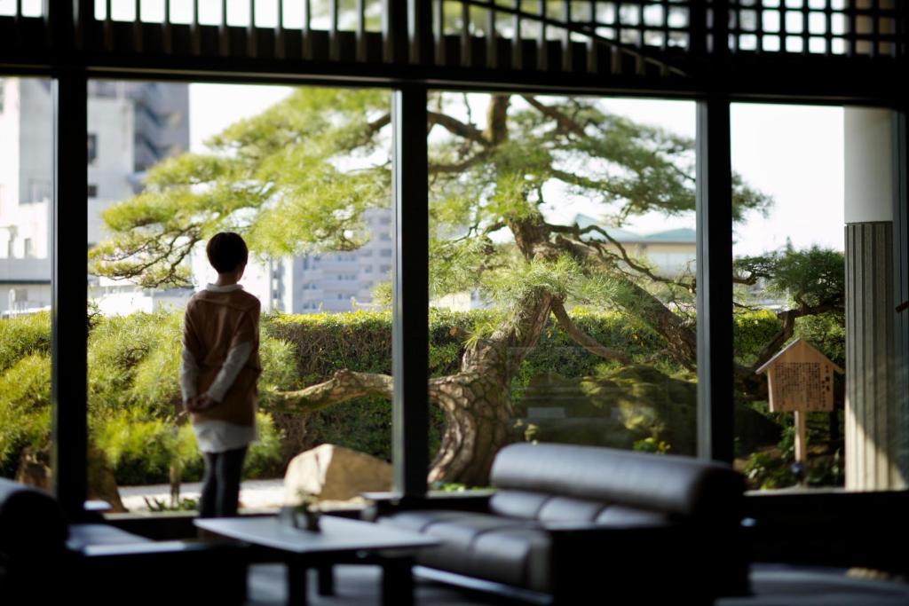 Un garçon qui regarde un arbre par une fenêtre dans l'établissement Dogo Kan, à Matsuyama