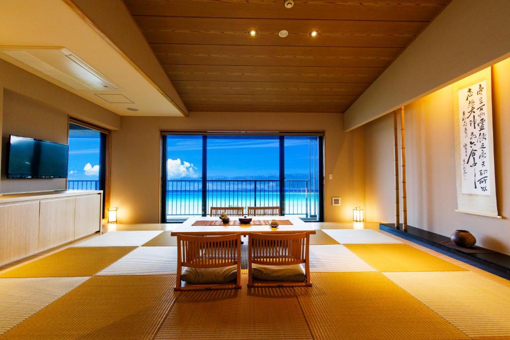 une pièce avec une table et des chaises et une grande fenêtre dans l'établissement Umino Ryotei Okinawa Nakamasou, à Onna