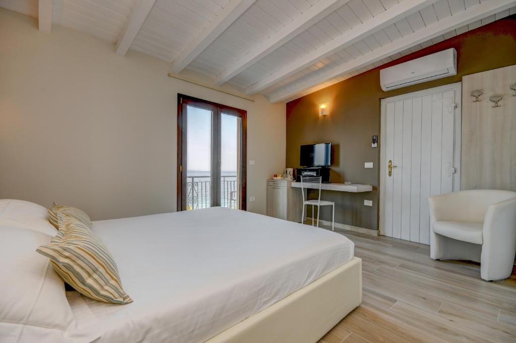 une chambre avec un grand lit blanc et une cuisine dans l'établissement VILLA GARUTI VILLAGE, à Padenghe sul Garda