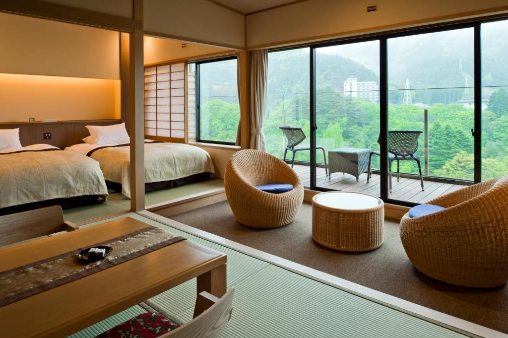 une chambre d'hôtel avec un lit, des chaises et des fenêtres dans l'établissement Kanaya Hotel Kinugawa, à Nikkō