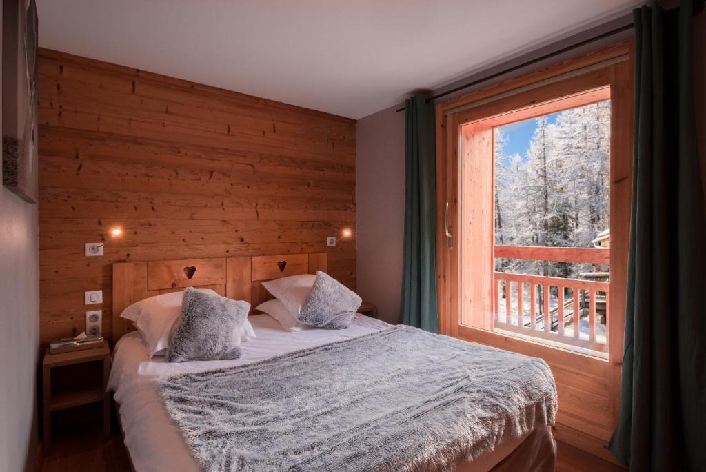 une chambre avec un lit et une grande fenêtre dans l'établissement Hotel & Restaurant Les Escondus, à Vars