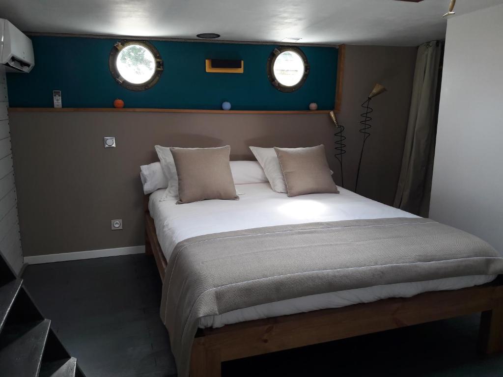 Cette petite chambre comprend un grand lit et 2 fenêtres. dans l'établissement Péniche La Belle Aimée, à Aigues-Mortes