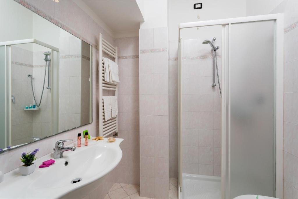une salle de bain blanche avec lavabo et douche dans l'établissement Hotel Cannes - in pieno centro, à Riccione