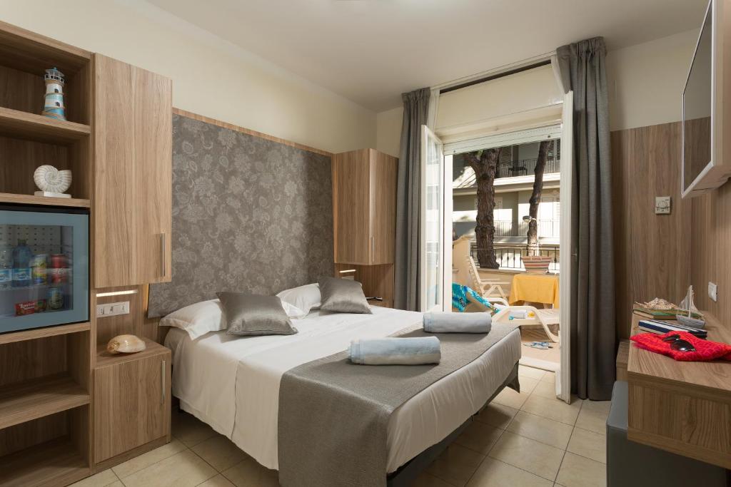 une chambre avec un lit et une porte coulissante en verre dans l'établissement Hotel Cannes - in pieno centro, à Riccione