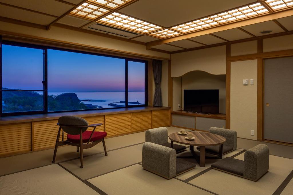 - un salon avec une table, des chaises et une grande fenêtre dans l'établissement Kiki Shiretoko Natural Resort, à Shari
