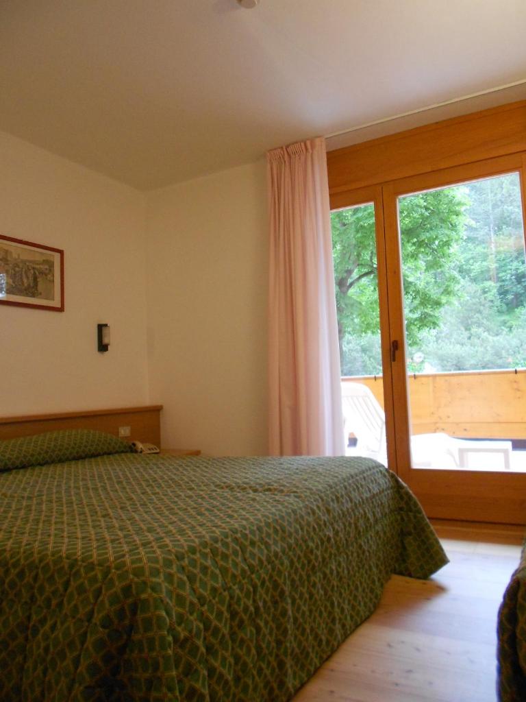 une chambre avec un lit et une grande fenêtre dans l'établissement Garni Lago Nembia, à San Lorenzo in Banale
