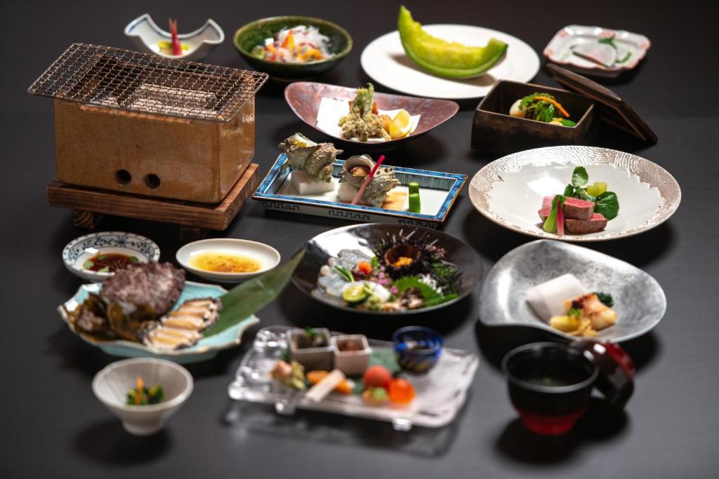 une table avec de nombreuses assiettes de nourriture dessus dans l'établissement IKI RETREAT by Onko Chishin, à Iki
