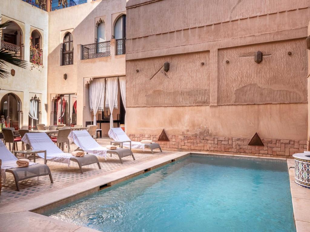 une piscine avec des chaises longues à côté d'un bâtiment dans l'établissement Riad Passali, à Marrakech