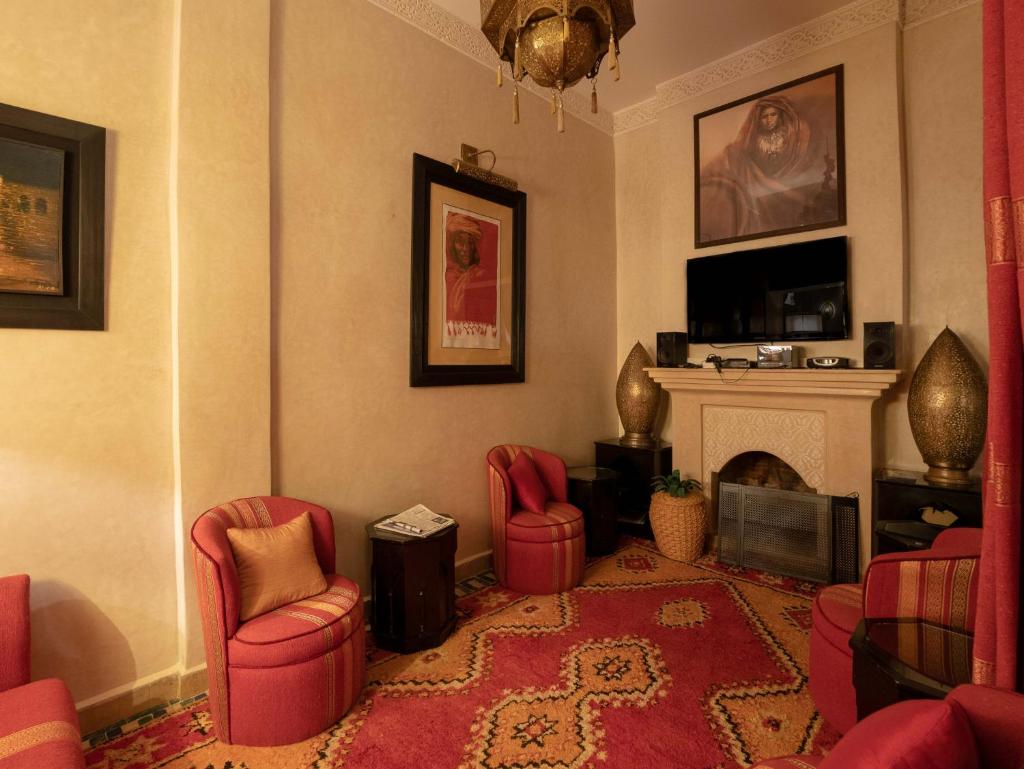 un salon avec des chaises rouges et une cheminée dans l'établissement Riad Passali, à Marrakech