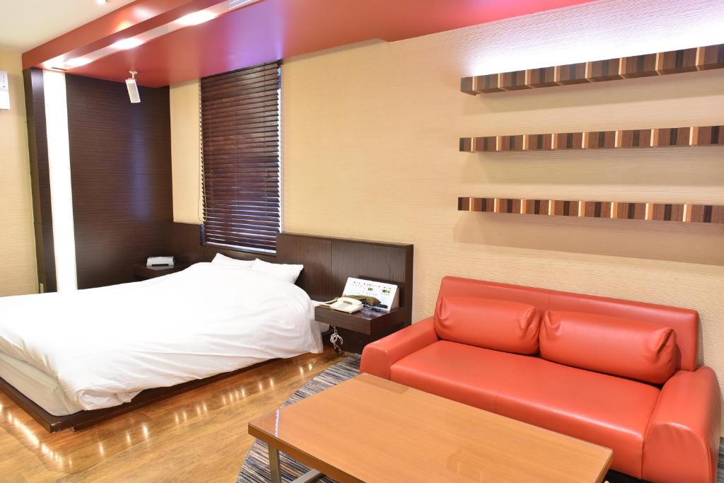 une chambre avec un lit et un canapé rouge dans l'établissement C-HOTEL affetto(Adult Only), à Sapporo