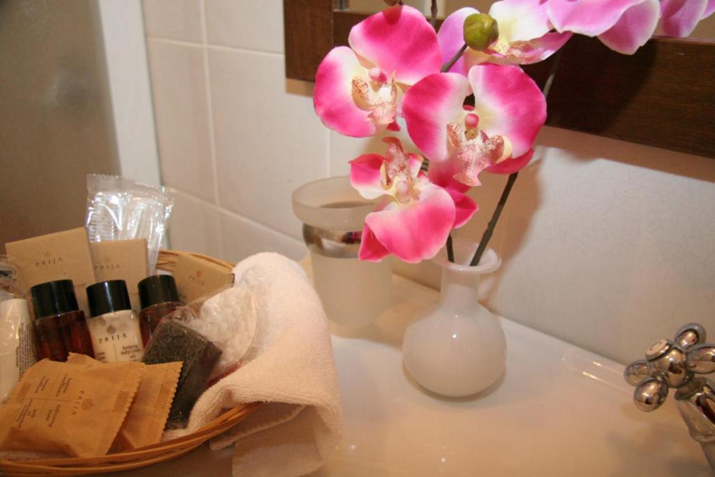 un vase blanc avec des fleurs roses sur un comptoir dans l'établissement Hotel U' Bais, à Scilla