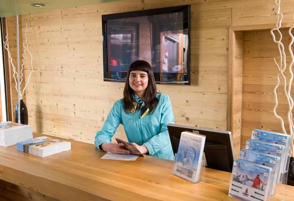 une femme assise à une table avec un ordinateur portable dans l'établissement Résidence Pierre & Vacances Les Constellations, à Belle Plagne
