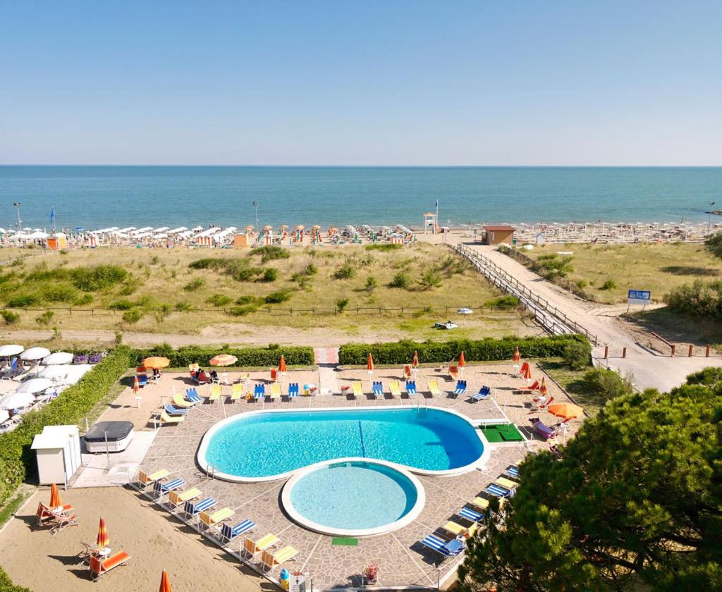 - une piscine avec des parasols et des chaises ainsi qu'une plage dans l'établissement Hotel Bertha Fronte Mare, à Lido di Jesolo