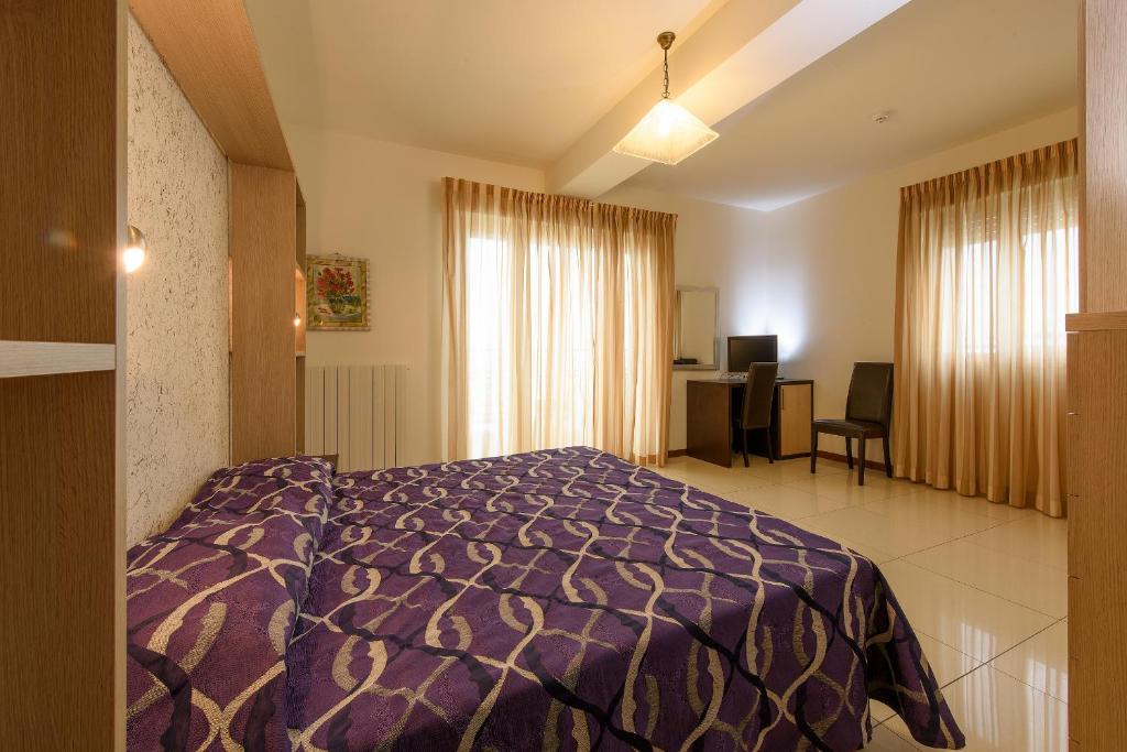 une chambre avec un lit violet et un bureau dedans dans l'établissement Hotel Residence Villa Jolanda, à Lido di Camaiore