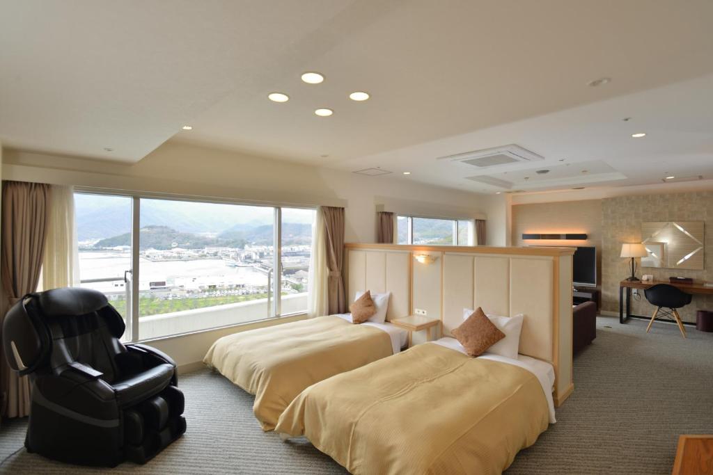 - 2 lits dans une chambre d'hôtel avec une grande fenêtre dans l'établissement Bay Resort Hotel Shodoshima, à Shodoshima
