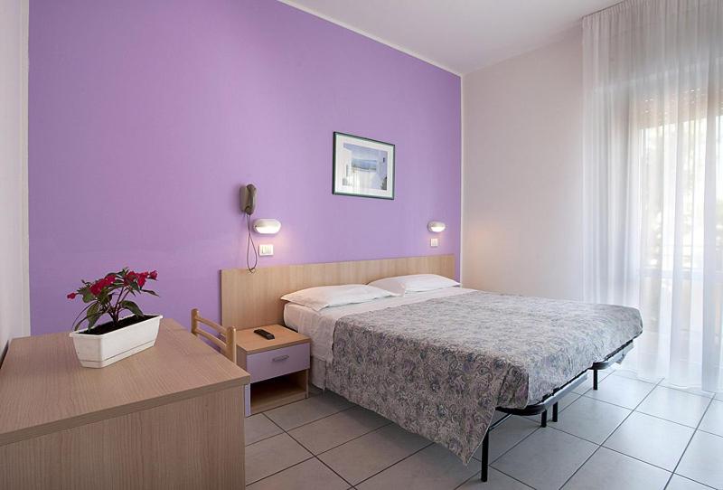 une chambre avec un lit et un mur violet dans l'établissement Hotel Giordo, à Rimini