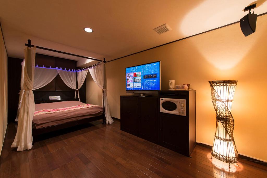 - une chambre avec un lit à baldaquin et une télévision dans l'établissement aloalo, à Fujikawaguchiko