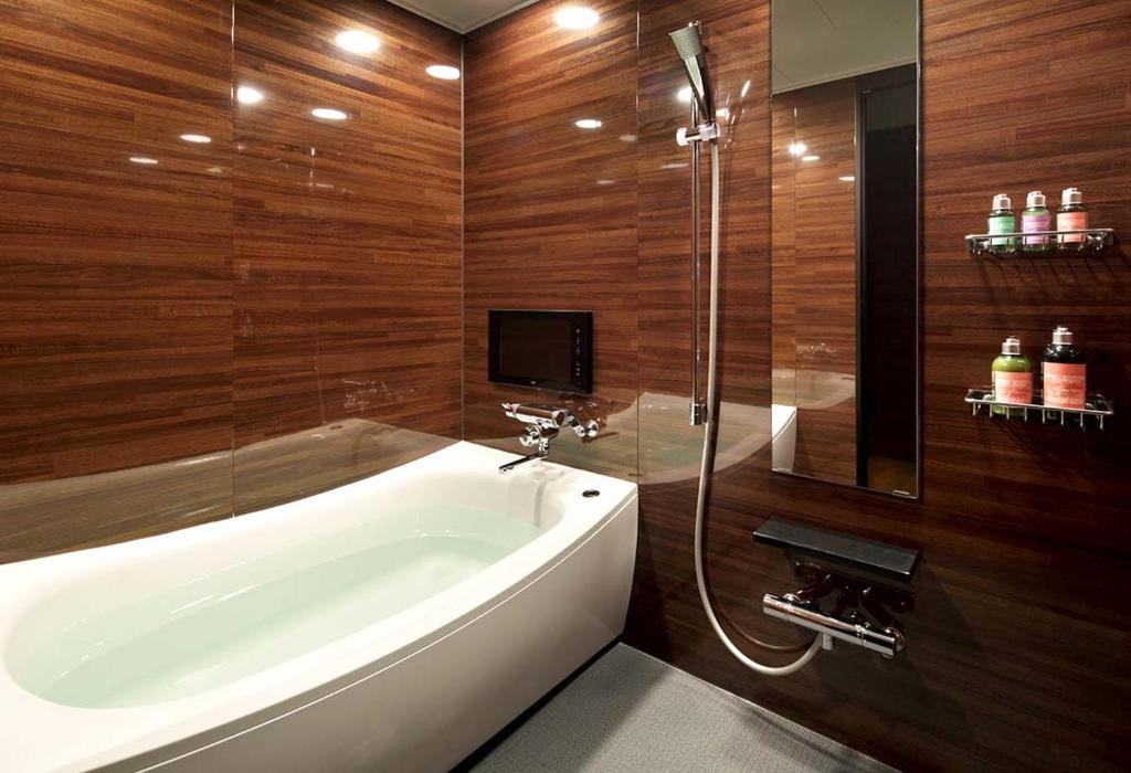 une salle de bain avec une baignoire blanche et une douche dans l'établissement Hotel UNO Nishikawaguchi Nishiguchi, à Kawaguchi