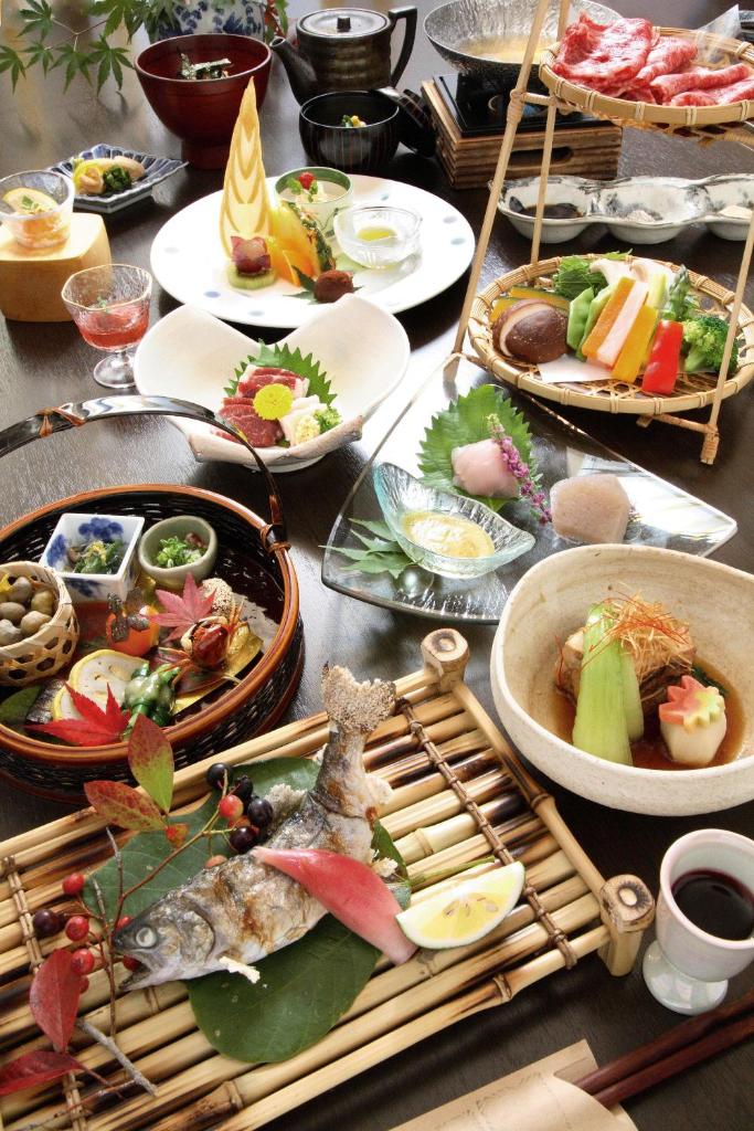 une table avec de nombreuses assiettes de nourriture dessus dans l'établissement Ryokan Kono-Yu, à Minamioguni