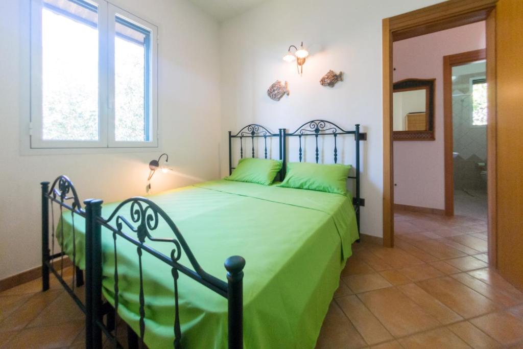 - une chambre avec un lit doté de draps verts et une fenêtre dans l'établissement Villa del Mito - Blue Marine, à Tricase