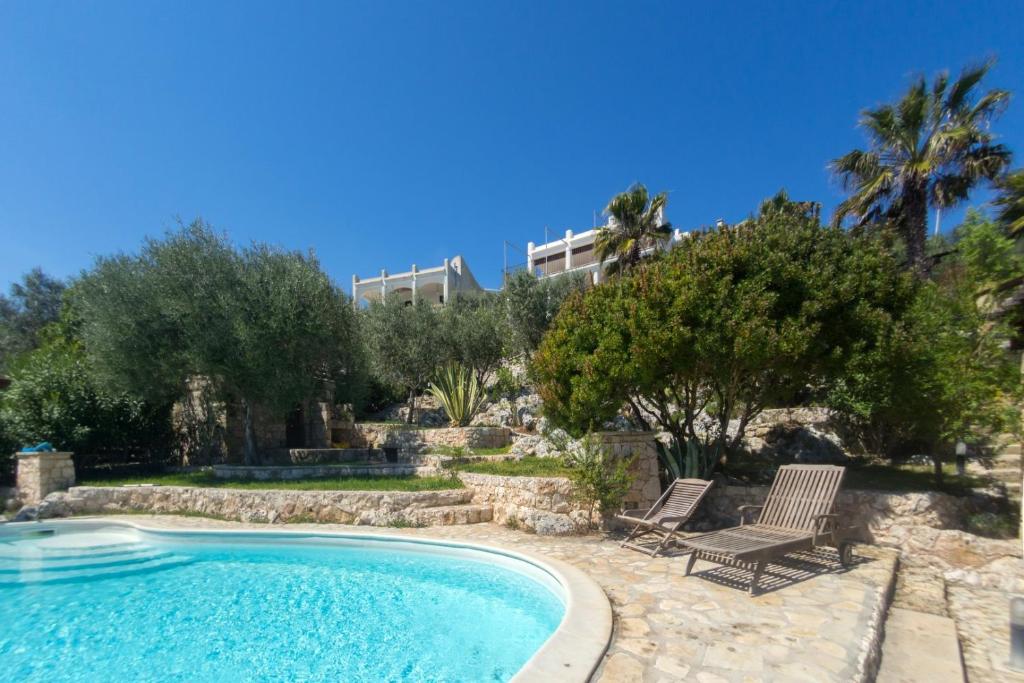 une piscine avec deux chaises et une maison en arrière-plan dans l'établissement Villa del Mito - Blue Marine, à Tricase