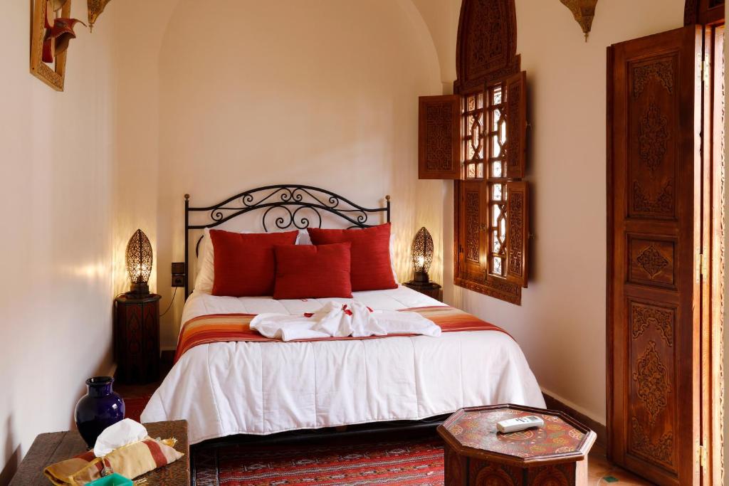une chambre avec un grand lit avec des oreillers rouges dans l'établissement Riad Daria Suites & Spa, à Marrakech