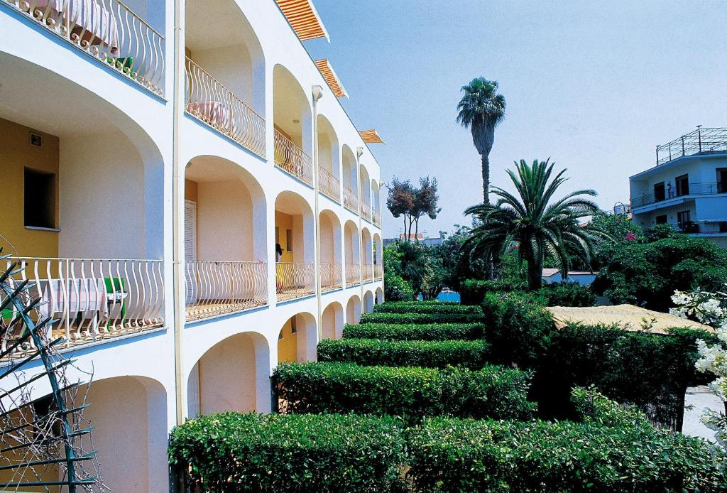 un bâtiment avec des buissons et des arbres à côté d'un bâtiment dans l'établissement Hotel San Giovanni Terme, à Ischia