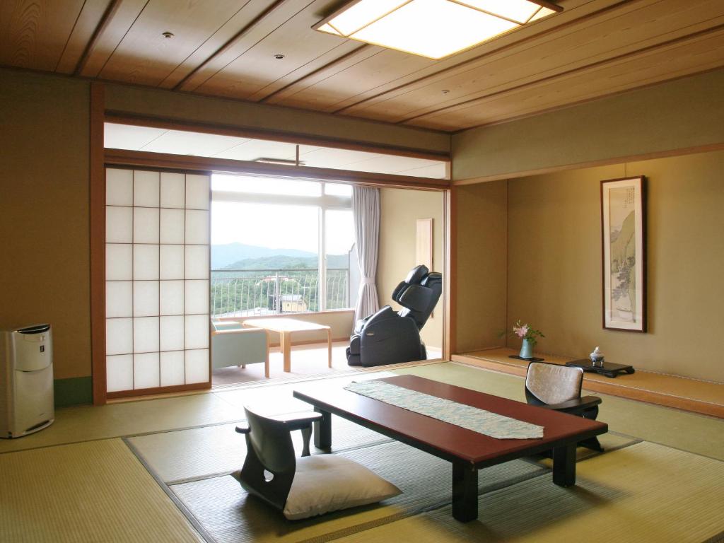 - un salon avec une table, des chaises et une grande fenêtre dans l'établissement Hyoe Koyokaku, à Kobe