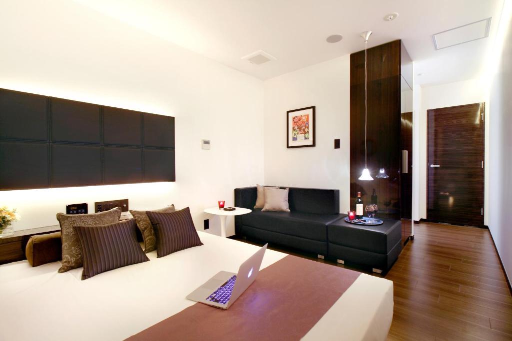 un salon avec un canapé et un ordinateur portable sur une table dans l'établissement Hotel DUO kinsicho, à Tokyo