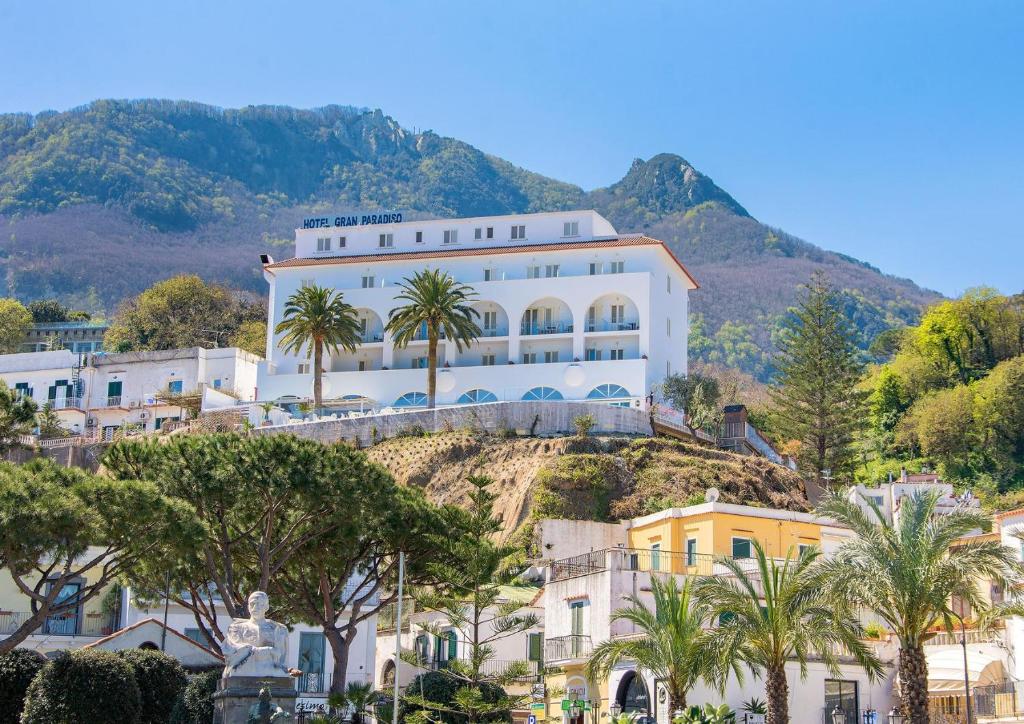 un grand bâtiment blanc sur une colline avec des palmiers dans l'établissement Hotel Gran Paradiso, à Ischia