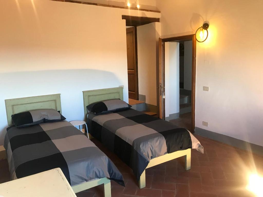 Cette chambre comprend deux lits et une table éclairée. dans l'établissement Casa Colle Petroso, à Radda in Chianti