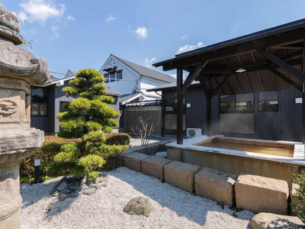 une maison avec un arbre dans la cour avant dans l'établissement Katsuragi Onsen Happuu No Yu, à Katsuragi