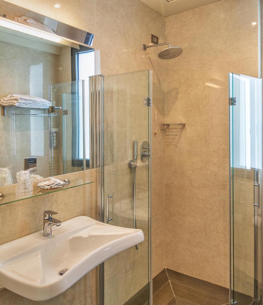 une salle de bain avec un lavabo et une douche en verre dans l'établissement Hotel Esplanade, à Marina di Pietrasanta