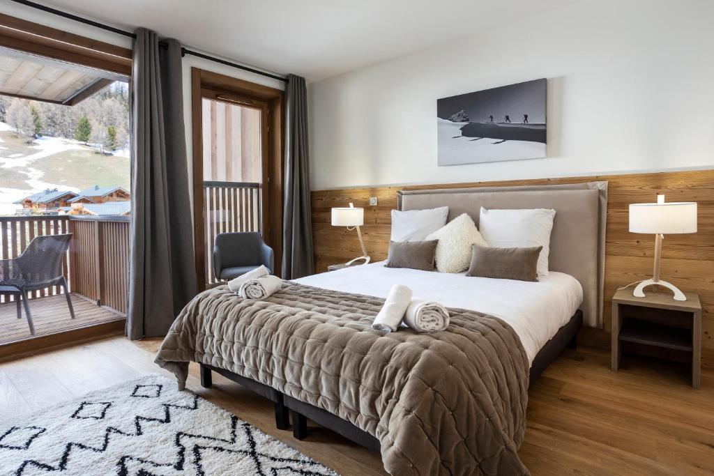 une chambre avec un grand lit et un balcon dans l'établissement TERRESENS - Le Diamant des Neiges, à Plagne 1800