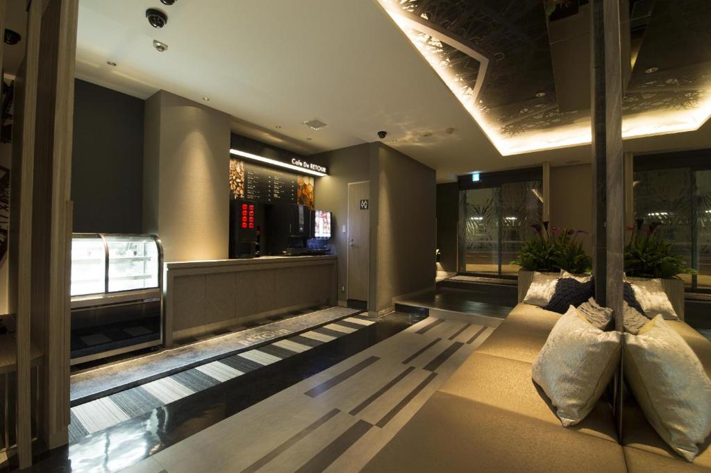 - un hall d'un immeuble avec un canapé et des fenêtres dans l'établissement ルトゥール難波 RetourNANBA 男塾ホテルグループ, à Osaka
