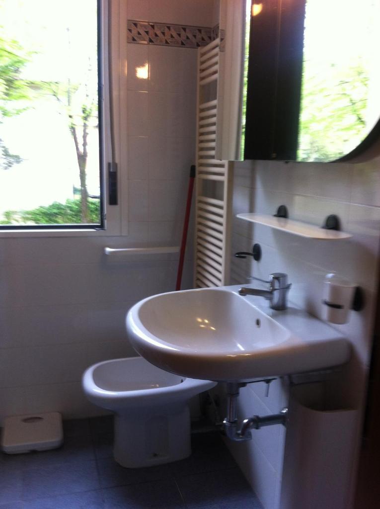 une salle de bain avec un lavabo et des toilettes et une fenêtre dans l'établissement Pensione Imperia, à Lignano Sabbiadoro