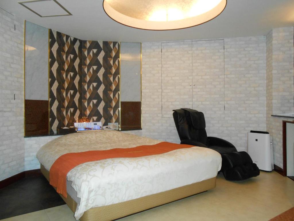 - une chambre avec un grand lit et une chaise noire dans l'établissement Hotel Regina, à Kashiwa
