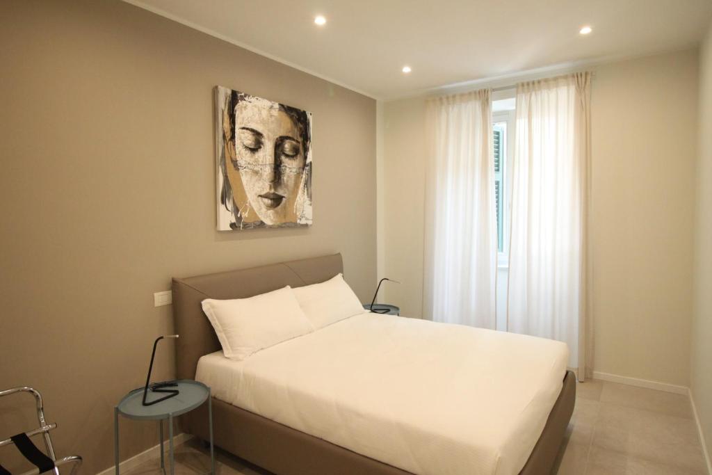 une chambre avec un lit blanc et un tableau au mur dans l'établissement Casa Vacanze Residence Ideale Suites and Apartments, à Alassio