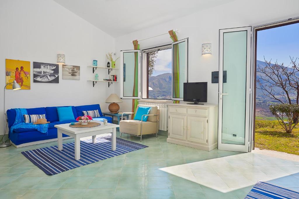 un salon avec un canapé bleu et une télévision dans l'établissement Villa Sirena - Scopello-Villas, à Scopello