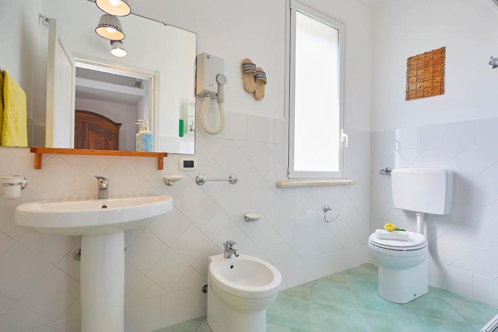 une salle de bain blanche avec un lavabo et des toilettes dans l'établissement Villa Delfino - Scopello-Villas, à Scopello