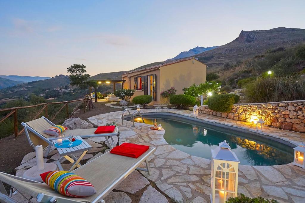 une arrière-cour avec une piscine entourée de chaises et une maison dans l'établissement Villa Delfino - Scopello-Villas, à Scopello