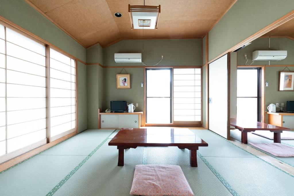 Cette chambre dispose d'une table et de fenêtres. dans l'établissement Sakura Ryokan Asakusa Iriya, à Tokyo