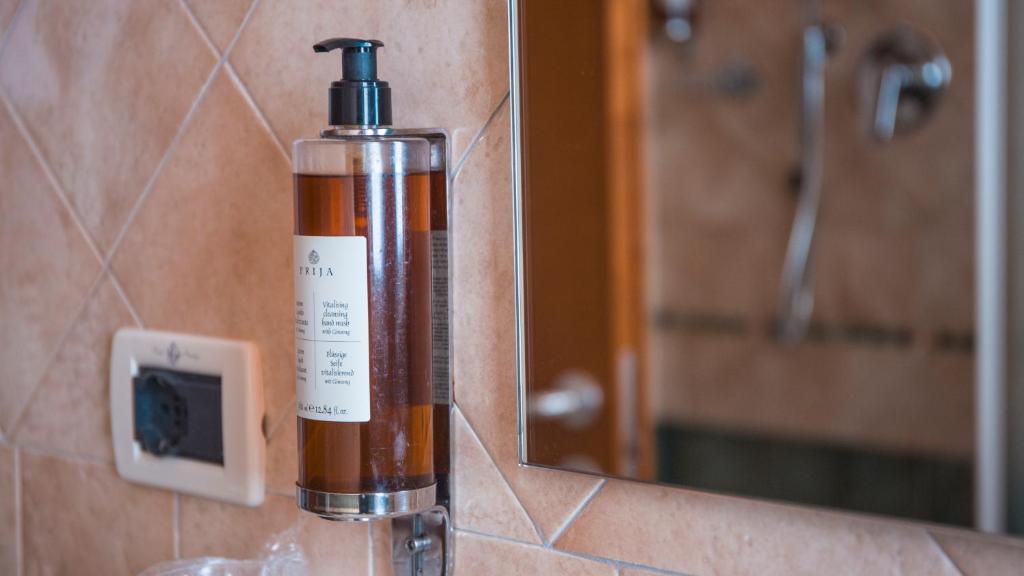 une bouteille de savon posée à côté d'un miroir dans l'établissement Hotel Prestige, à Montesilvano 131 autres photos