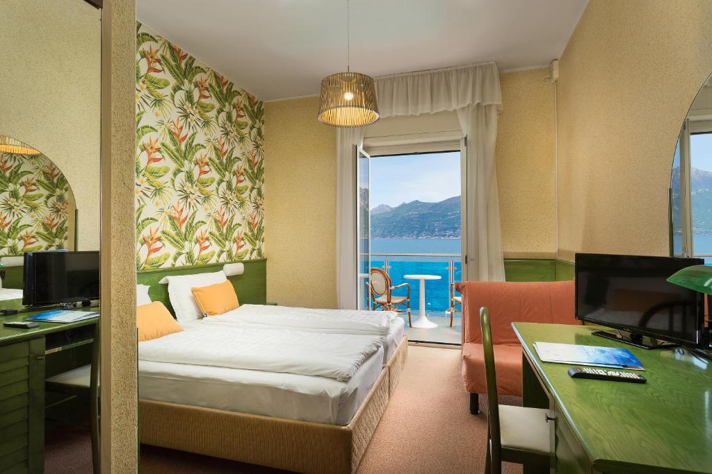 une chambre d'hôtel avec un lit, un bureau et une fenêtre dans l'établissement Hotel Caribe - Garda Lake Collection, à Brenzone