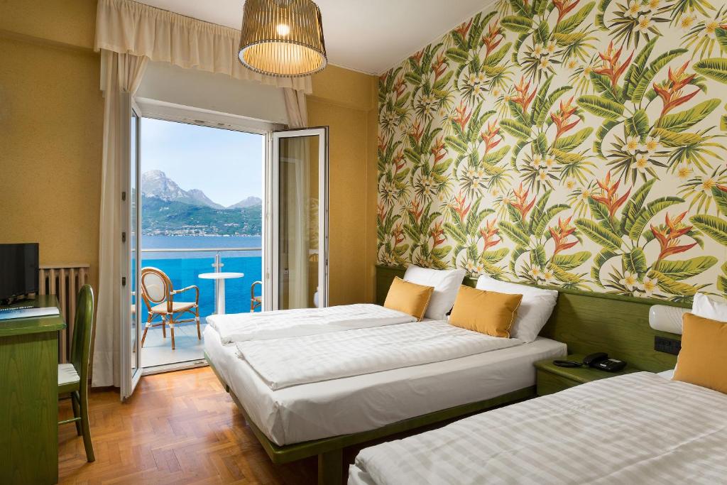 une chambre d'hôtel avec deux lits et un balcon dans l'établissement Hotel Caribe - Garda Lake Collection, à Brenzone 28 autres photos